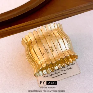Bold gold pleated wide cuff bracelet with textured metallic finish and elastic cord