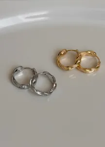 Detailansicht minimalistischer gedrehter Creolen in polierter Gold- und Silberoptik