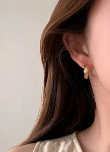 Detaillierte Nahaufnahme eines minimalistischen goldenen Creolen-Ohrrings am Ohr des Models