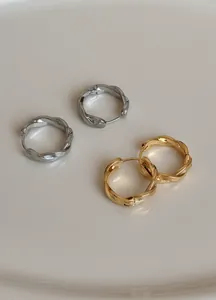 Detailansicht von goldenen und silbernen gedrehten Creolen mit minimalistischer Flechtstruktur