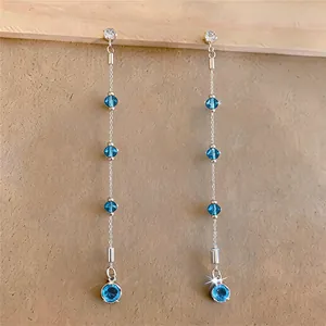 Detail shot of elegant long tassel earrings with blue zircon crystals and silver finish