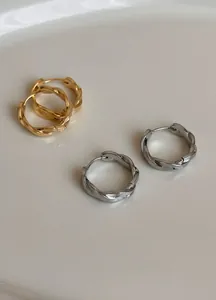 Detailaufnahme minimalistischer gedrehter Seil-Creolen in polierter Gold- und Silberoptik