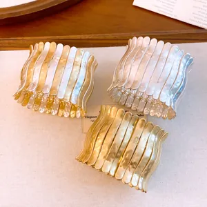 Detailansicht von drei plissierten elastischen Metallarmbändern in Gold und Silber