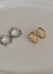 Nahaufnahme von minimalistischen gedrehten Creolen in elegantem Gold- und Silberfinish.