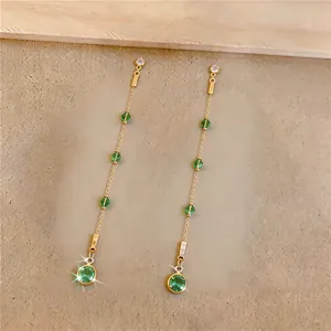 Close-up of elegant long tassel earrings with green zircon and faceted beads