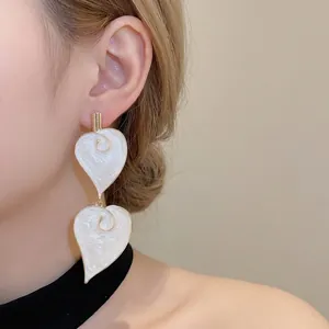 Elegante witte hartvormige emaille hangoorbellen met goudkleurige spiraalaccenten