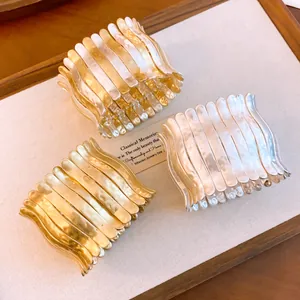 Nahaufnahme breiter, gewellter elastischer Manschettenarmbänder in Gold und Silber