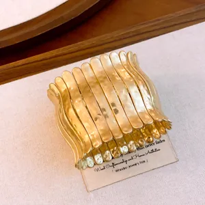 Detaillierte Nahaufnahme eines goldfarbenen gehämmerten Stretch-Armbands mit Falten