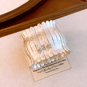 Detaillierte Makroansicht eines silbernen gefalteten Metallarmbands mit wellenförmigen Segmenten