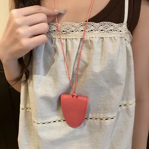 Détail du collier porte-lunettes en cuir rose porté sur un haut en dentelle