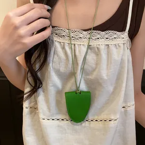 Gros plan d'un collier porte-lunettes en cuir vert vif porté sur un caraco blanc