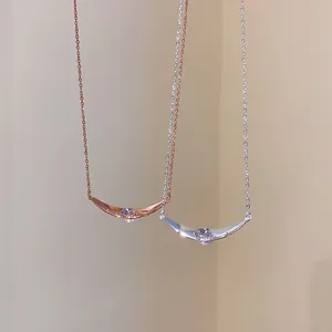 Detailansicht von Halsketten mit gebogenem Anhänger und Zirkonia in Roségold und Silber.
