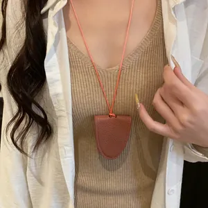 Gros plan d'un collier porte-lunettes en cuir marron porté comme accessoire fonctionnel.