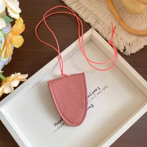 Vue détaillée du collier porte-lunettes en cuir rose texturé sur un plateau blanc