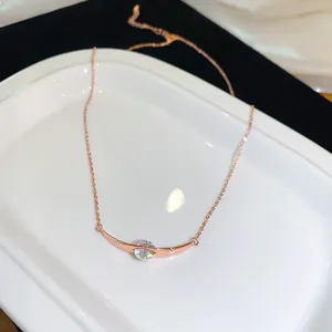 Nahaufnahme einer roségoldenen Halskette mit gebogenem Anhänger und funkelndem Zirkoniastein.
