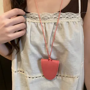 Vue détaillée d'un collier porte-lunettes en cuir rose sur un haut en dentelle blanche