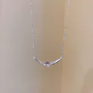Detailansicht einer minimalistischen, silberfarbenen Halskette mit gebogenem Zirkonia-Anhänger