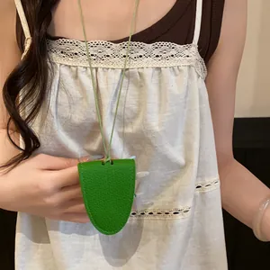 Détail d'un collier porte-lunettes en cuir vert grainé, porté comme accessoire de mode chic