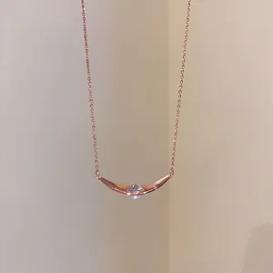 Nahaufnahme einer eleganten Halskette aus Roségold mit geschwungenem Zirkon-Anhänger