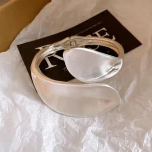 Detailed close-up of a heavy-duty silver twisted bangle with overlapping leaf design