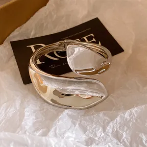 Detail view of a silver heavy-duty twisted hollow bangle on elegant packaging paper.