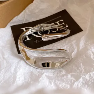 Close-up of silver heavy-duty twisted hollow bangle with high-polish metallic finish.