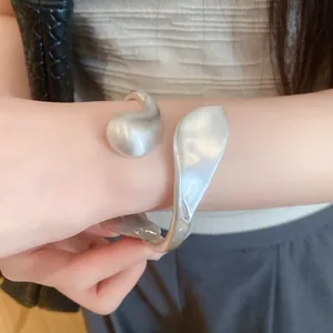 Detail view of a silver sculptural cuff bracelet with a brushed matte finish.