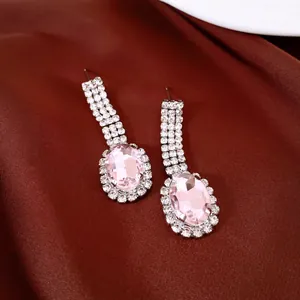 Close-up of elegant silver earrings with oval pink gemstones and brilliant rhinestone halos