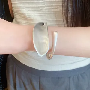 Close-up of a minimalist sculptural silver-toned wrap bangle with a unique twisted design.