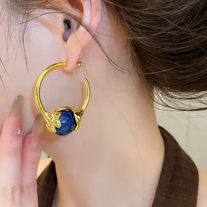 Detailansicht eines vintage 18K vergoldeten C-Ohrrings mit einer blauen Steinperle.