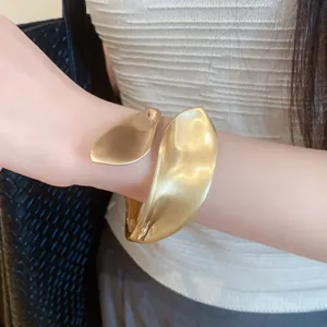 Detail showing the matte gold brushed texture of the bold twisted cuff bracelet