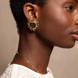 Detailansicht eines goldenen Herz-Sonnenohrrings aus Edelstahl bei einem Model