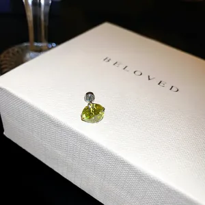 Gros plan d'une boucle d'oreille en zircone jaune lime étincelante sur une boîte blanche