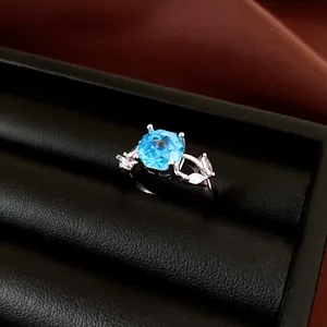 Elegante zilveren ring met een sprankelende blauwe steen in een zwart lederen doosje.