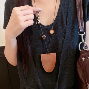 Vintage brown leather pendant necklace featuring decorative beads and ribbon bow on model