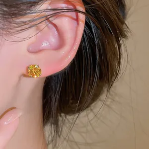Vue macro élégante d'une boucle d'oreille puce en zircone jaune étincelante sur l'oreille