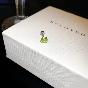Gros plan d'une boucle d'oreille clou en zircon vert citron avec fermoir sur boîte.