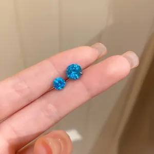 Détail de clous d'oreilles en zircon bleu vibrant avec tiges en argent pour l'échelle.