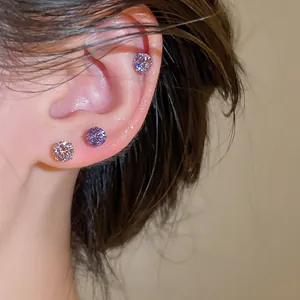Vue détaillée de trois boucles d'oreilles en zircon violet portées sur l'oreille