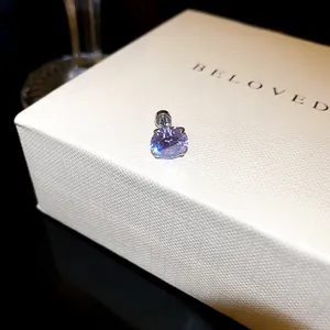 Gros plan d'une boucle d'oreille en zircon violet sur une boîte à bijoux crème