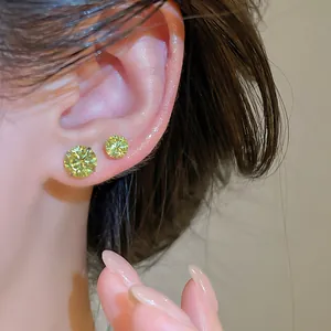 Gros plan de boucles d'oreilles en zircon vert citron étincelantes portées sur l'oreille