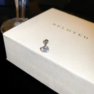 Vue détaillée d'une boucle d'oreille en zircone cubique sur une boîte cadeau blanche chic
