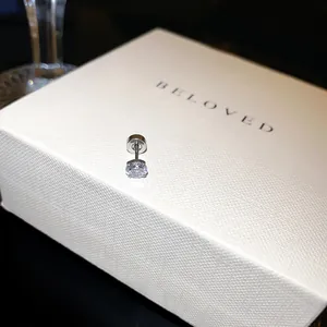 Gros plan d'une boucle d'oreille en zircone étincelante sur une boîte cadeau blanche