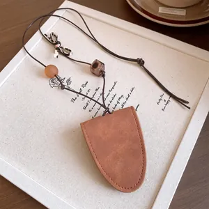 Vue détaillée d'un collier pochette à clés en cuir marron avec perles et nœud léopard.