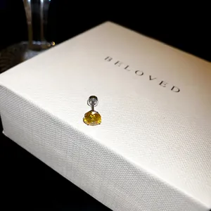 Gros plan détaillé montrant un clou d'oreille en zircon jaune étincelant avec fermoir