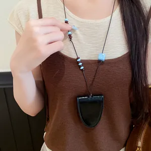 Vue détaillée d'un collier long en cuir avec des perles et un charme de dé bleu