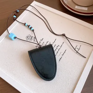 Détail d'un collier pendentif en cuir noir avec perles bleues sur fond de toile artistique