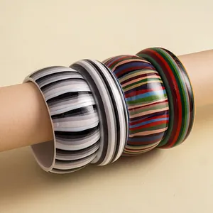 Close-up of retro resin bangles with colorful striped patterns on a stand.