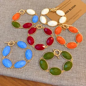 Collection of colorful oval resin bracelets with gold-tone metal frames on fabric