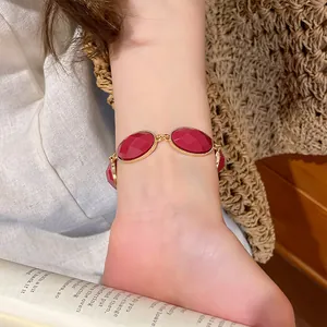 Close-up of elegant gold chain bracelet with red oval resin stones worn on a wrist